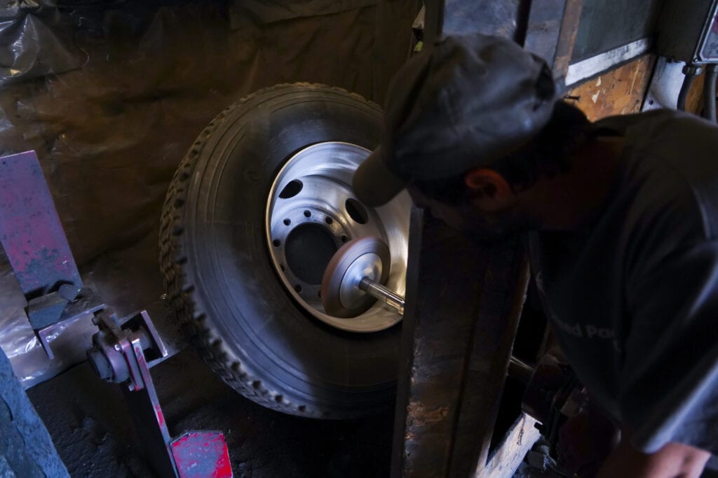 photo of man working in shop shining chrome wheel